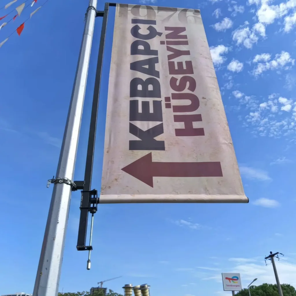 Tabela fiyatları 3 Cadde üzerindeki aydınlatma direğine monte edilmiş Tabelamatik pole banner